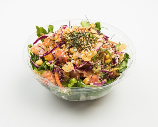 Closeup de uma salada com repolho roxo e carne, milho e legumes fatiados em uma tigela de vidro
