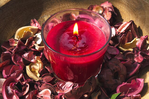 Closeup queimando vela vermelha entre pétalas de rosa