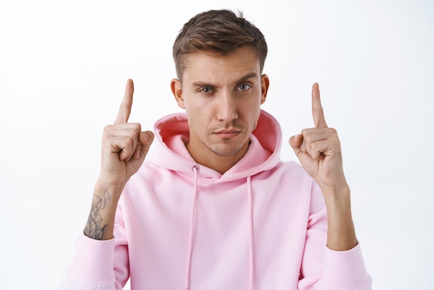 Closeup retrato de homem macho atrevido confiante com olhar de cabelo loiro com câmera de olhar confiante apontando os dedos para cima diga para visitar a loja online clique no link ou leia o fundo branco do banner