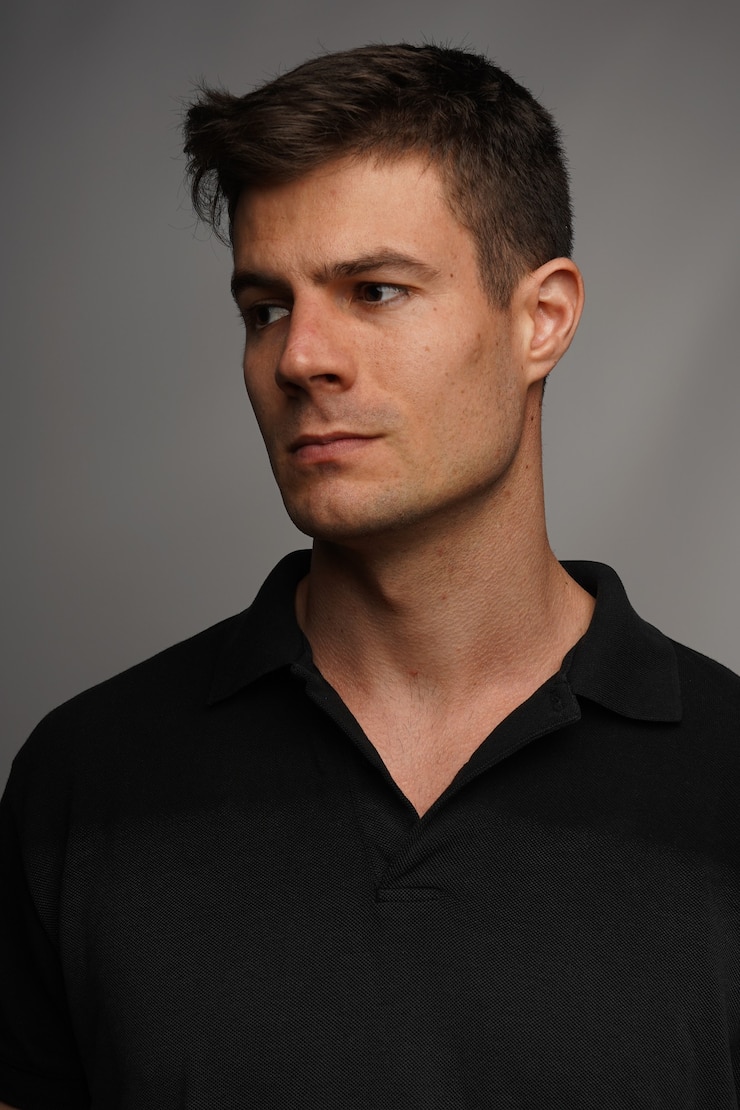 Foto grátis closeup retrato de um homem atraente em uma camiseta preta contra uma parede cinza