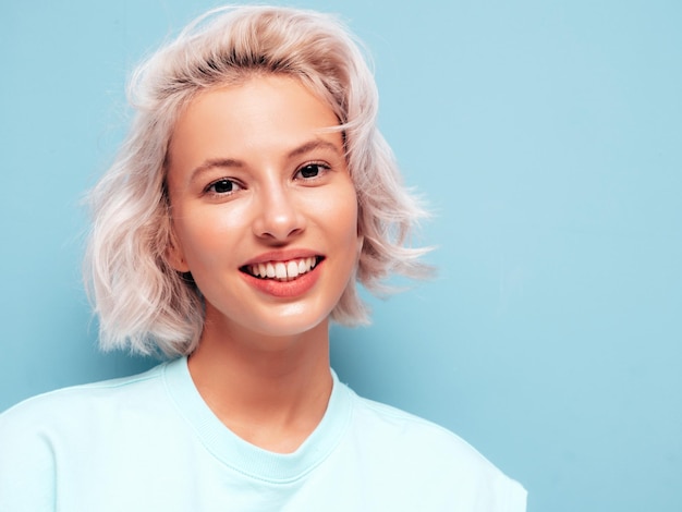 Closeup retrato de uma jovem linda mulher sorridente em roupas da moda de verão Mulher despreocupada sexy posando perto da parede azul no estúdio Modelo loiro positivo se divertindo e enlouquecendo Alegre e feliz