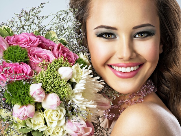 Closeup retrato de uma linda garota feliz com flores nas mãos. mulher jovem e atraente segurando o buquê de flores da primavera