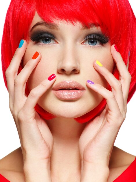 Closeup rosto de uma linda garota com unhas brilhantes e multicoloridas.