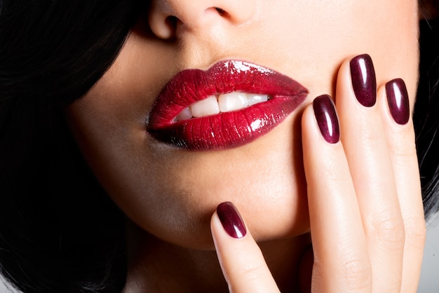 Foto grátis closeup rosto de uma mulher com lindos lábios vermelhos sensuais e unhas escuras