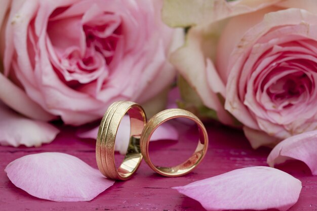 Closeup tiro de anéis de noivado com lindas rosas cor de rosa na mesa