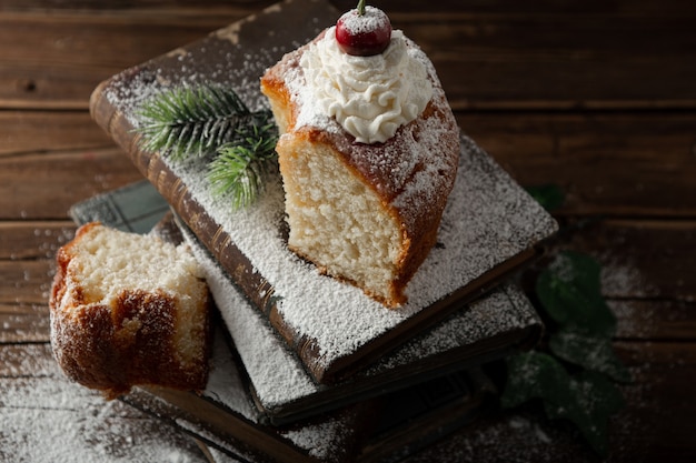 Closeup tiro de deliciosa sobremesa com creme, açúcar de confeiteiro e uma cereja no topo dos livros