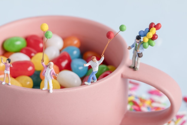 Closeup tiro de figuras de pessoas com balões em uma xícara com doces coloridos