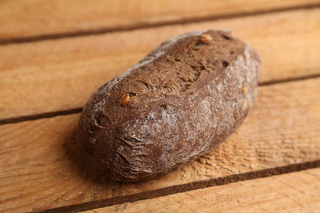 Closeup tiro de pão integral caseiro com pedaços de nozes em uma superfície de madeira