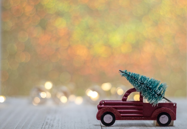 Closeup tiro de um brinquedo de carro com uma árvore de Natal e luzes desfocadas ao fundo