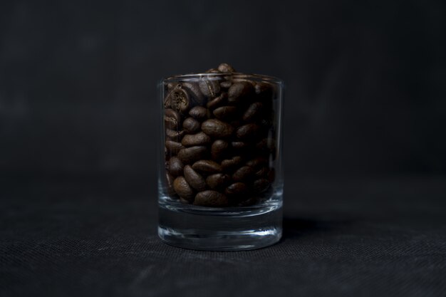 Closeup tiro de um copo de café em grão em uma superfície escura