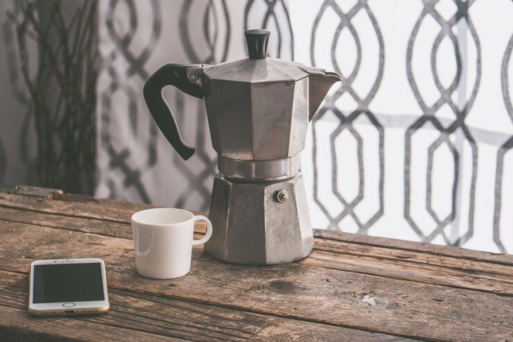 Foto grátis closeup tiro de um smartphone com uma caneca branca e um bule de chá cinza numa superfície de madeira