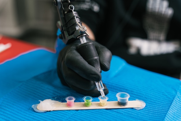 Closeup tiro de um tatuador misturando cores em um copo de plástico