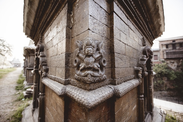 Closeup tiro de uma parede com escultura em um templo hindu no Nepal