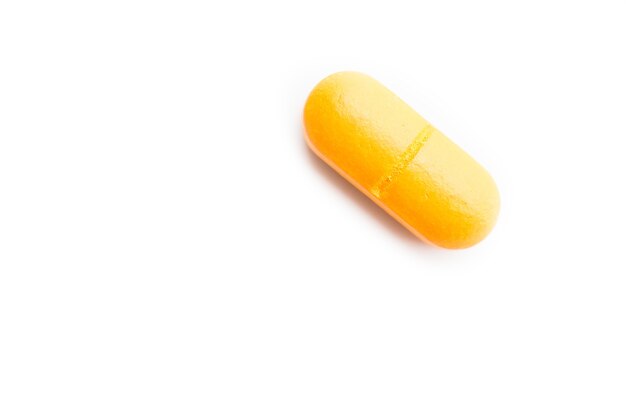 Closeup tiro de uma pílula amarela em uma superfície branca