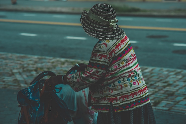 Foto grátis closeup tiro de uma velha mulher de chapéu segurando uma carruagem de carrinho