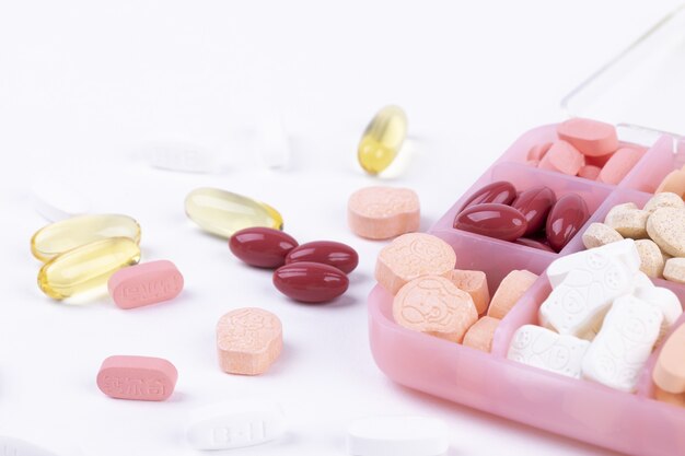 Closeup tiro de vários produtos farmacêuticos em um recipiente para medicamentos em um fundo branco