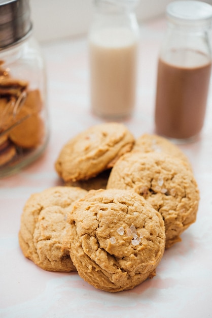 Closeup tiro vertical de saborosos biscoitos em uma superfície branca com leite com chocolate