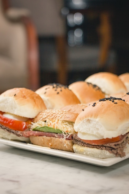 Closeup vertical de deliciosos sanduíches em um prato branco sobre uma mesa de mármore