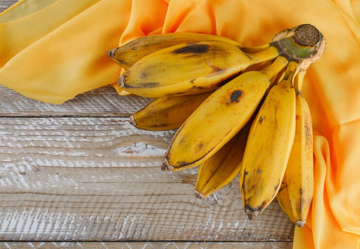 Foto grátis cluster de banana em madeira e têxteis.