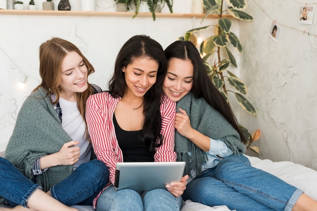 Foto grátis coberto com meninas cobertor sentado e olhando para a tela do tablet