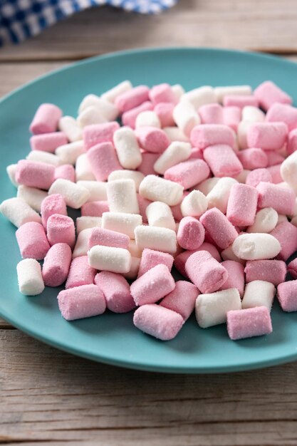 Cobertura de marshmallows doces em um prato azul na mesa de madeira