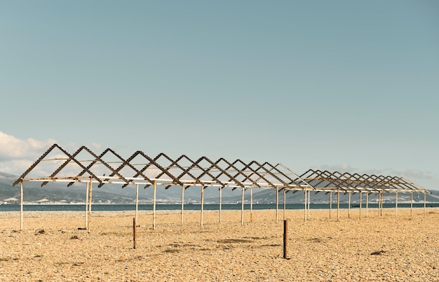 Coberturas velhas do sol em uma praia de seixos da cidade Costa do Mar Negro praia calma vazia em um dia ensolarado O céu está queimado ao meio-dia baía do mar e no fundo são as montanhas do Cáucaso Amostras pastel calmantes