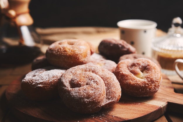 Foto grátis cobra donuts com açúcar de confeiteiro e café químico em uma mesa de madeira