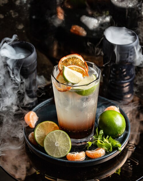 Cocktail de citrinos com fatias de laranja e limão em torno de copos fumados