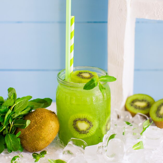 Cocktail de kiwi servido com pedaços de kiwi e gelo em frasco de vidro