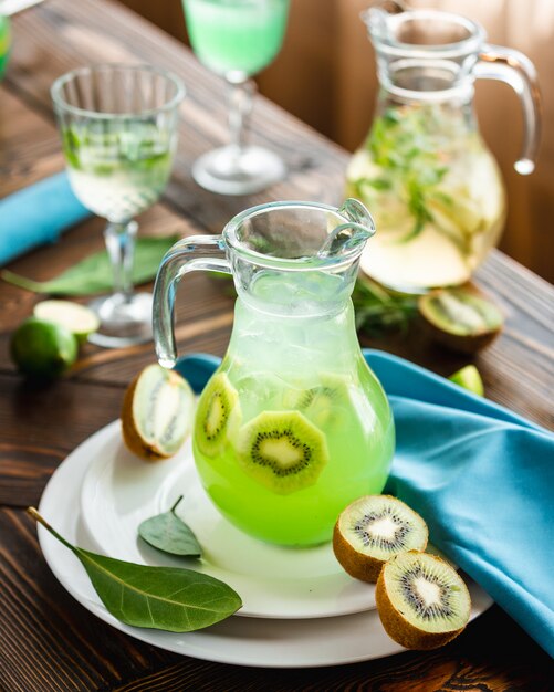 Cocktail de kiwi vermelho com cubos de limão e gelo em um prato branco.