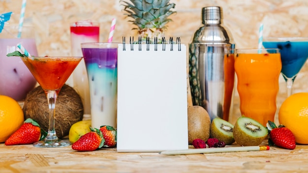 Cocktail e frutas tropicais com bloco de notas em branco