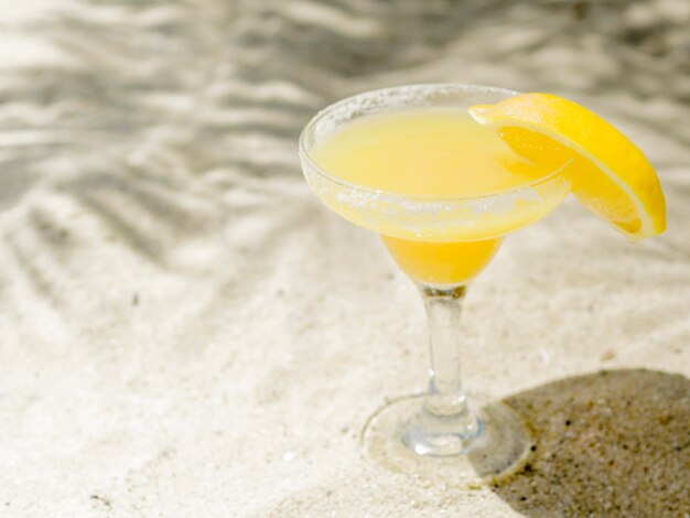 Cocktail fresco de laranja brilhante na areia