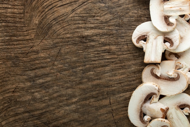 Cogumelos brancos frescos fatiados na mesa de madeira marrom