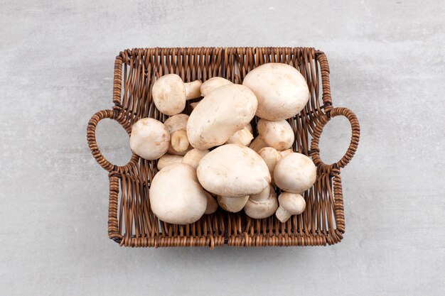 Cogumelos em uma cesta de vime, na mesa de mármore.