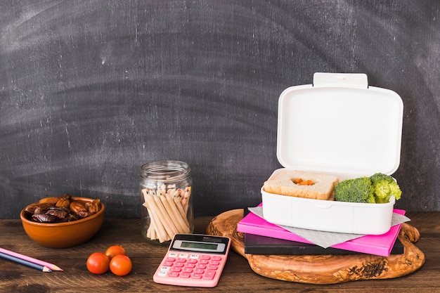 Coisas de escola e comida perto de quadro-negro