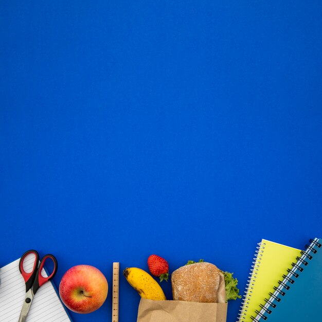 Foto grátis coisas de escola e sanduíche no fundo azul