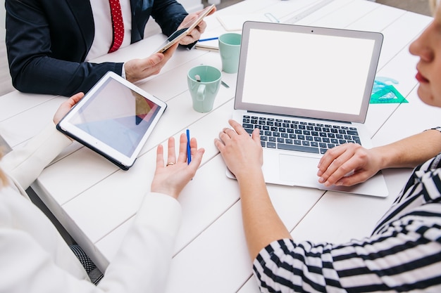 Colegas com dispositivos na mesa de trabalho