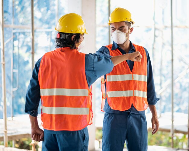 Colegas com equipamentos de segurança trabalhando com plantas