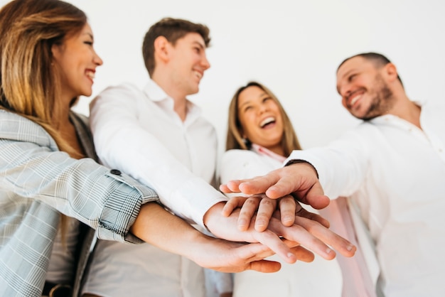 Colegas de escritório sorridentes colocando as mãos juntas