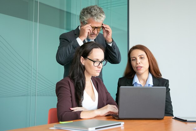 Colegas de trabalho assistindo a apresentação do projeto no computador, olhando para a tela do laptop aberto