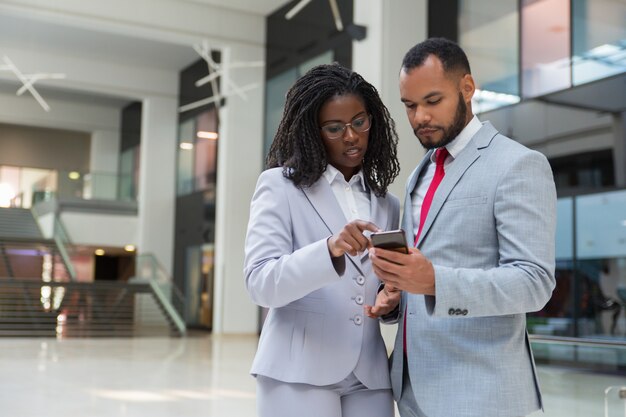 Colegas de trabalho focado com smartphone