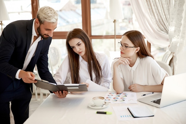 Colegas de trabalho jovens estão discutindo diagramas e relatórios financeiros anuais