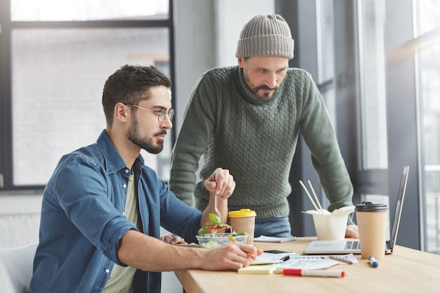 Colegas de trabalho masculinos no escritório com almoço