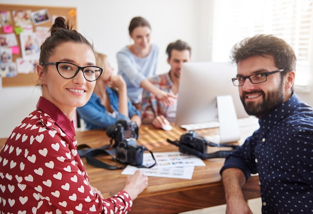 Colegas de trabalho no escritório com câmeras fotográficas e um computador