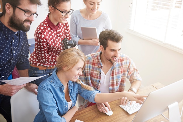 Colegas de trabalho no escritório com câmeras fotográficas e um computador