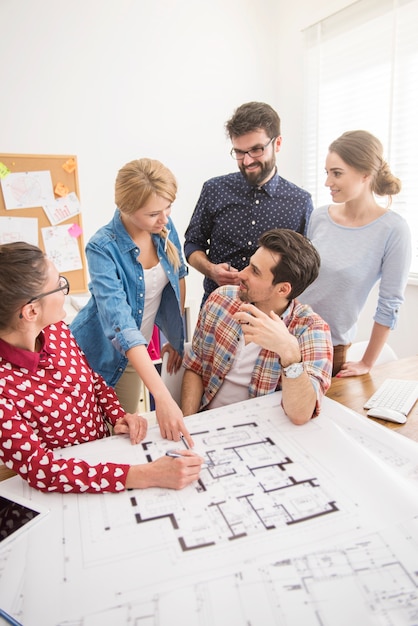 Colegas de trabalho no escritório com planos de arquitetura e um computador