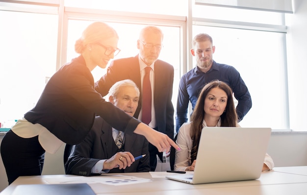 Colegas de trabalho olhando para um computador e falando sobre o trabalho no escritório