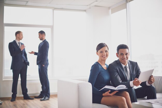 Colegas de trabalho que revêem o relatório no sofá