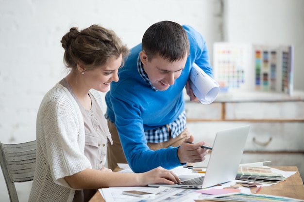 Colegas de trabalho, sorrindo, enquanto olhando para laptop