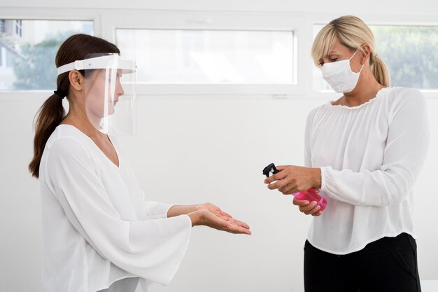 Colegas de trabalho usando proteção facial e desinfetante para as mãos